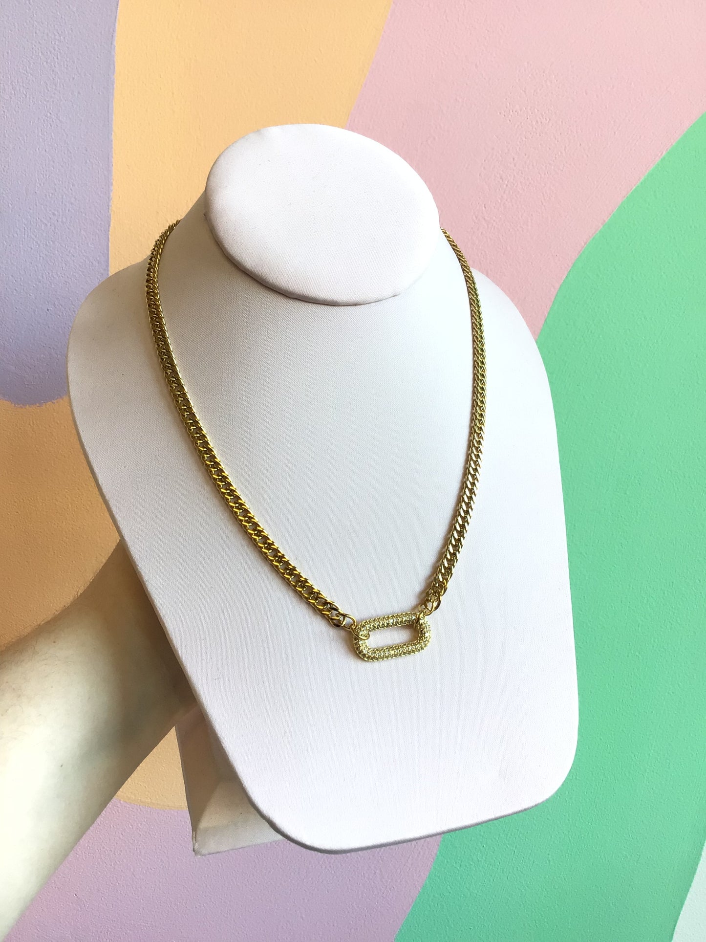 Glittering Statement Titanium Necklace shown on product stand in front of wavy colorful background