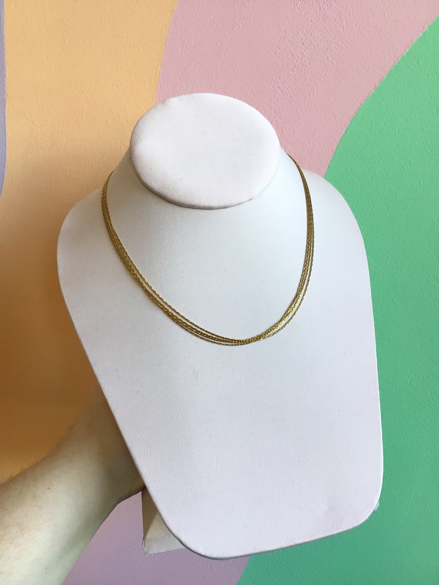Airy Layered Titanium Necklace show on product stand in front of wavy colorful background