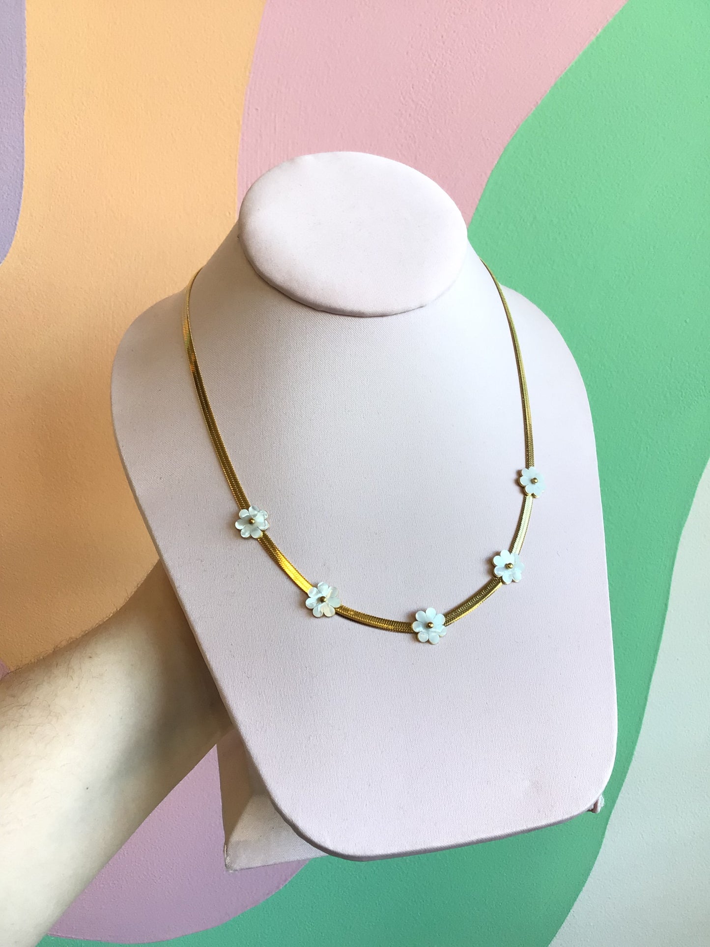 Flat Daisy Titanium Chain shown on product stand in front of wavy colorful background