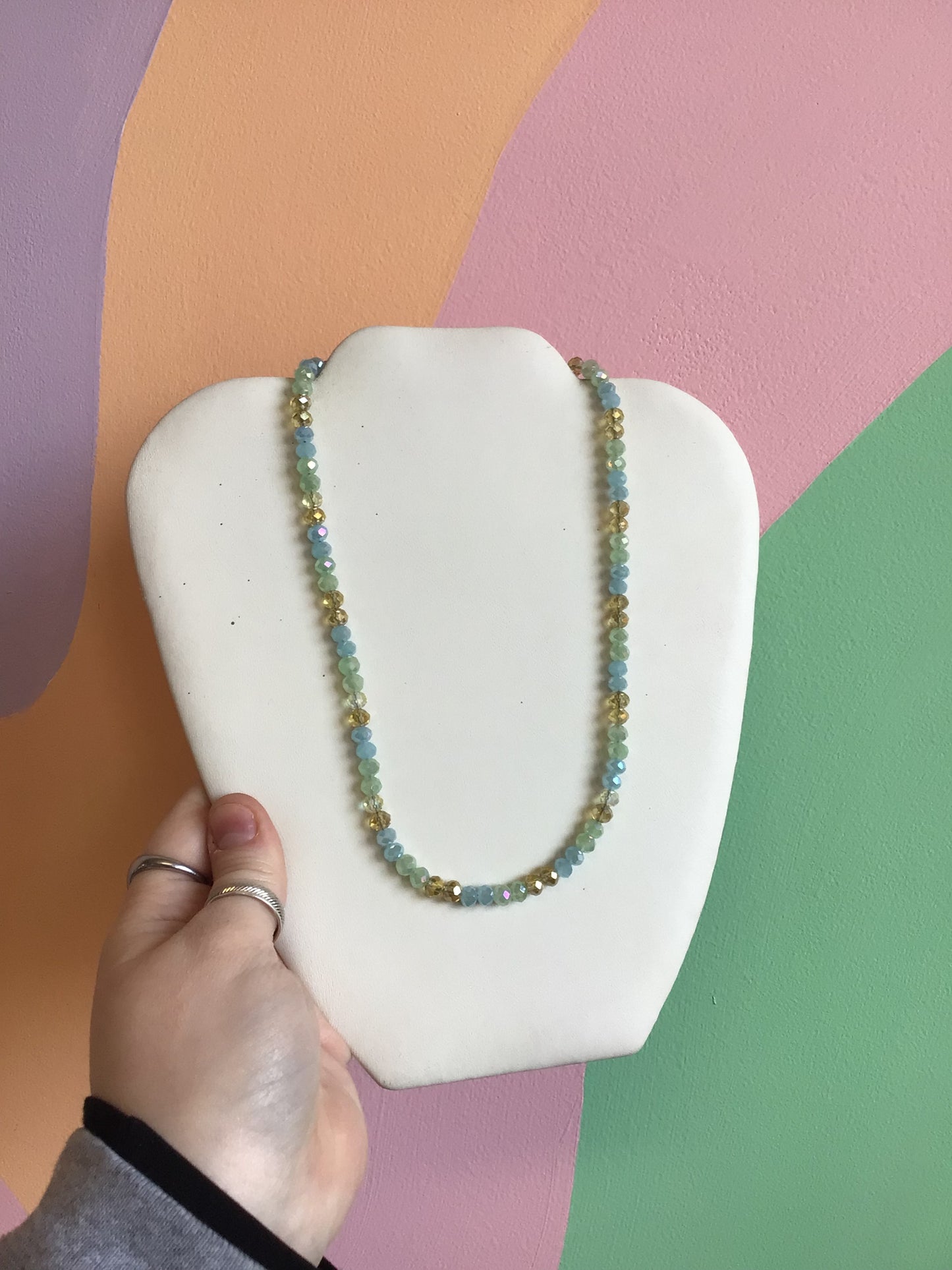 A necklace made up of faceted glass beads in golds, pastel blues, and pastel greens.