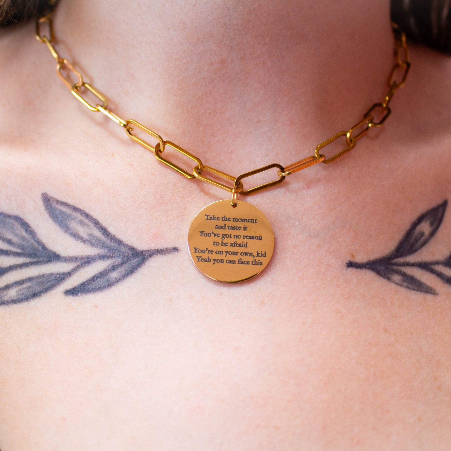 Close up of engraved necklace around model's neck. Reads "Take the moment and taste it You've got no reason to be afraid You're on your own, kid Yeah you can face this" a Taylor Swift Lyric