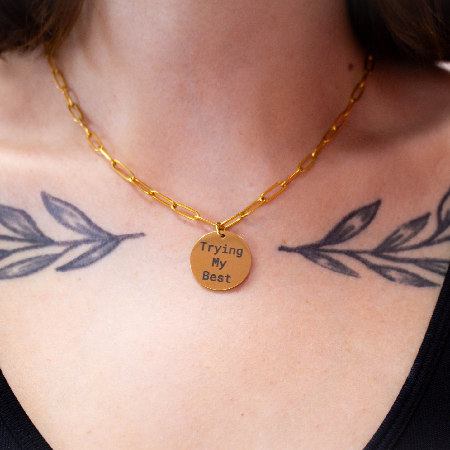 Close up of gold engraved charm necklace "Trying my best" on model's neck