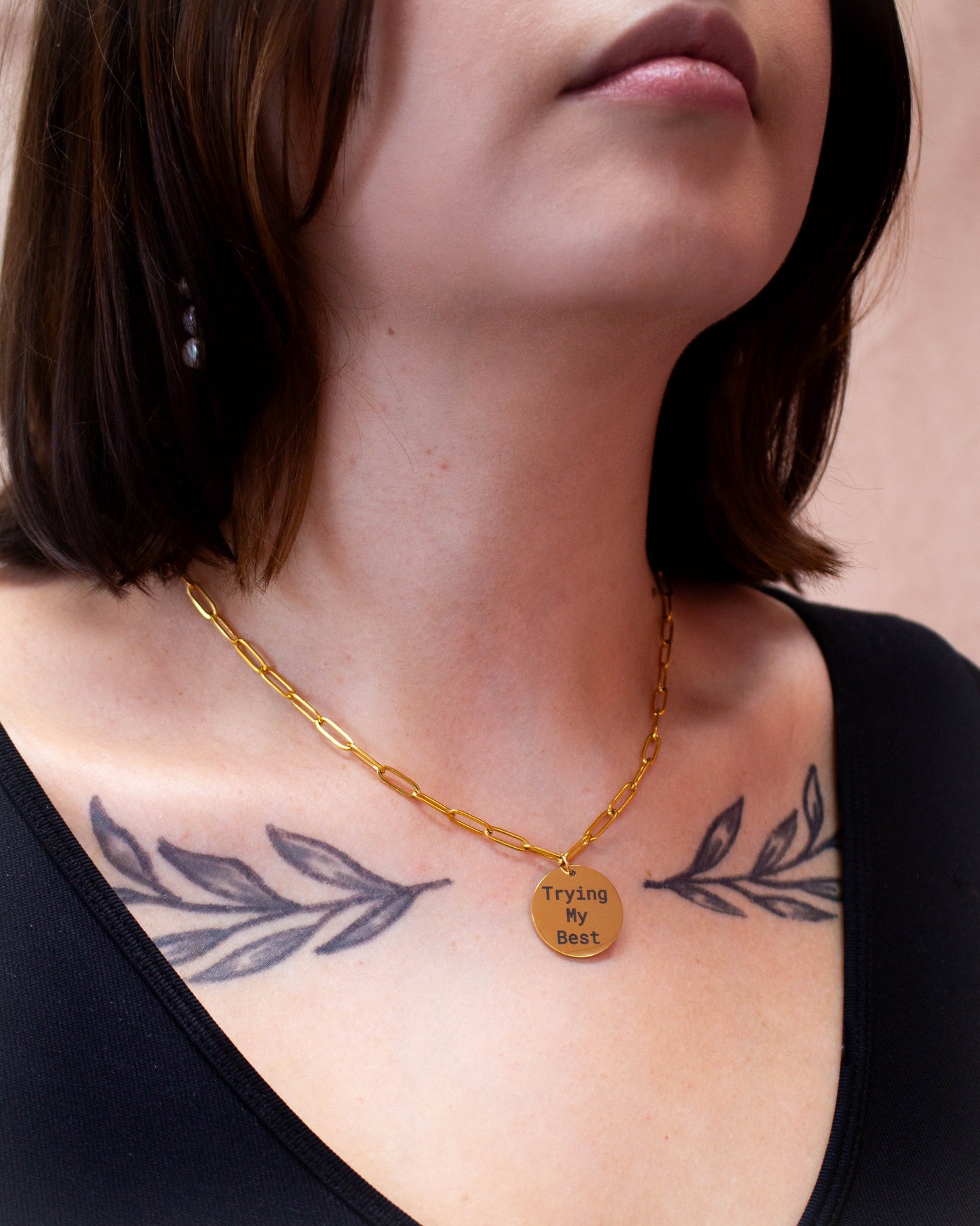 "Trying my best" engraved gold titanium necklace on model's neck, three quarters view