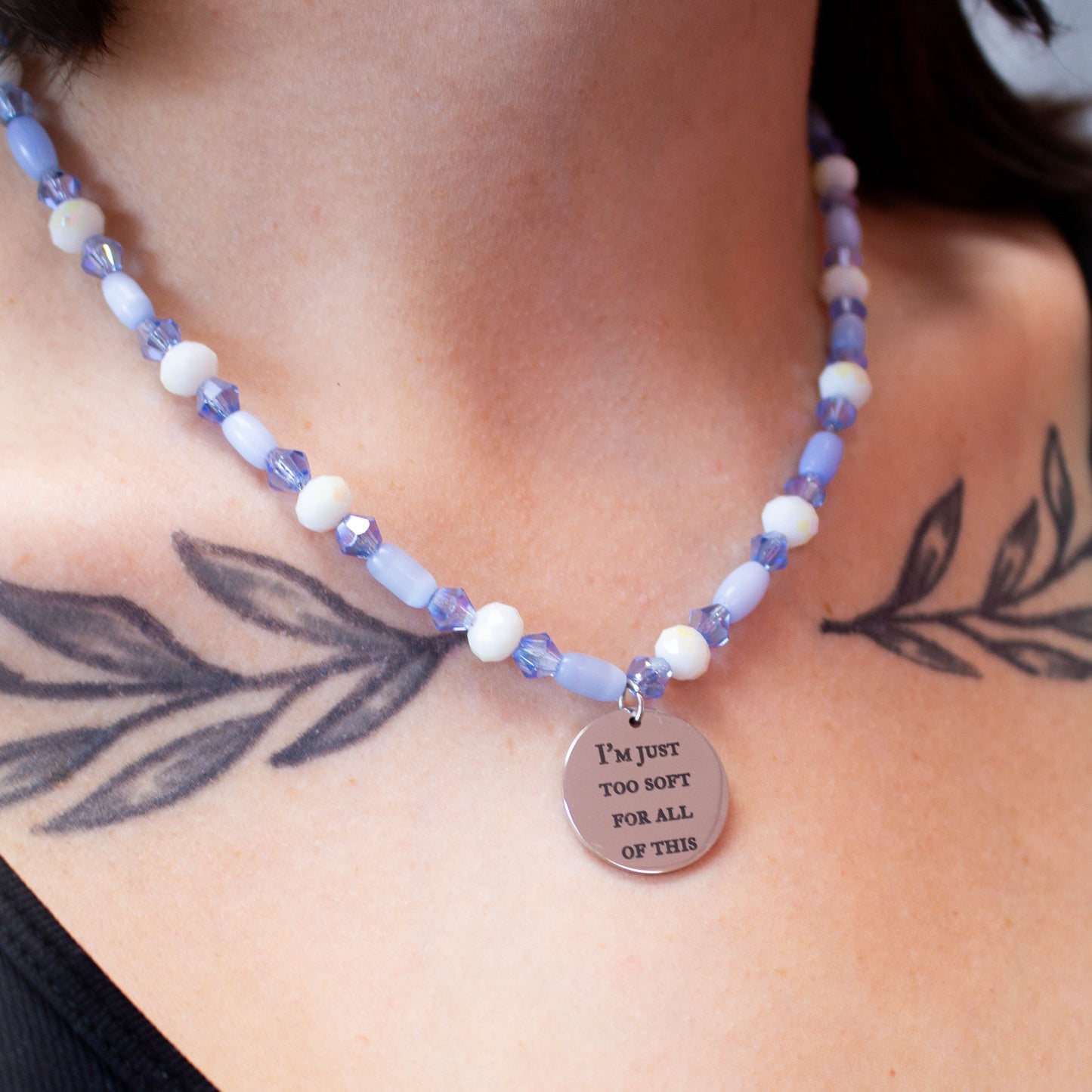 Purple glass beaded necklace with engraved charm reading "I'm just too soft for all of this" a Taylor Swift lyric