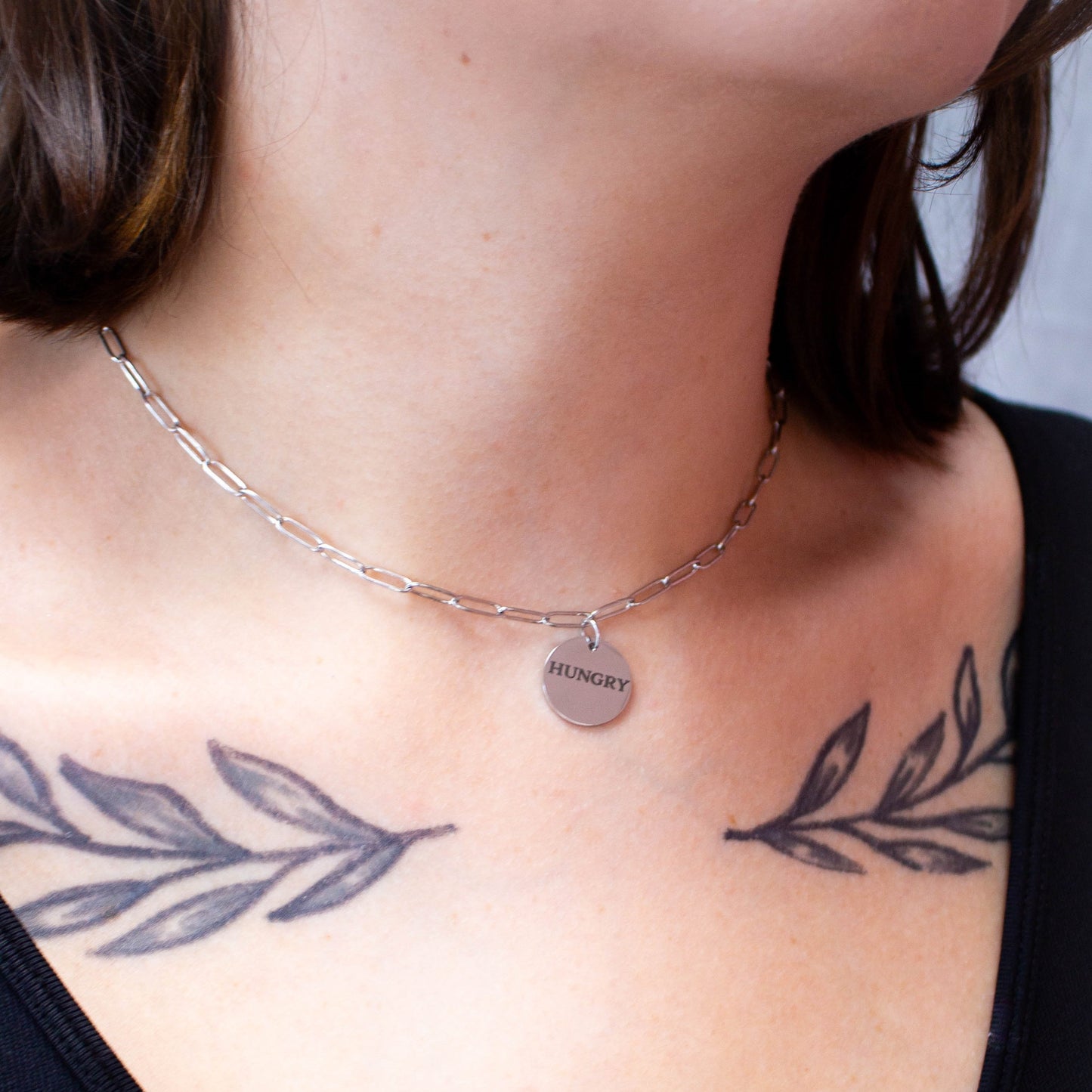 Close up of "Hungry" engraved necklace on model's neck
