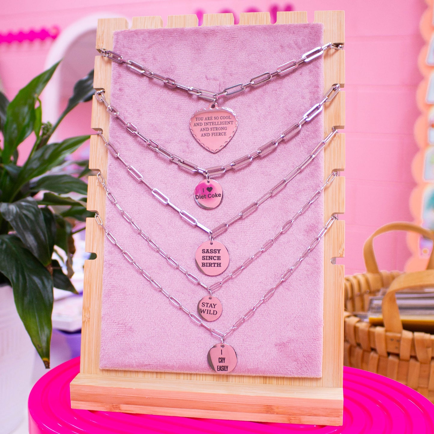 Silver engraved necklaces with phrases displayed on product stand