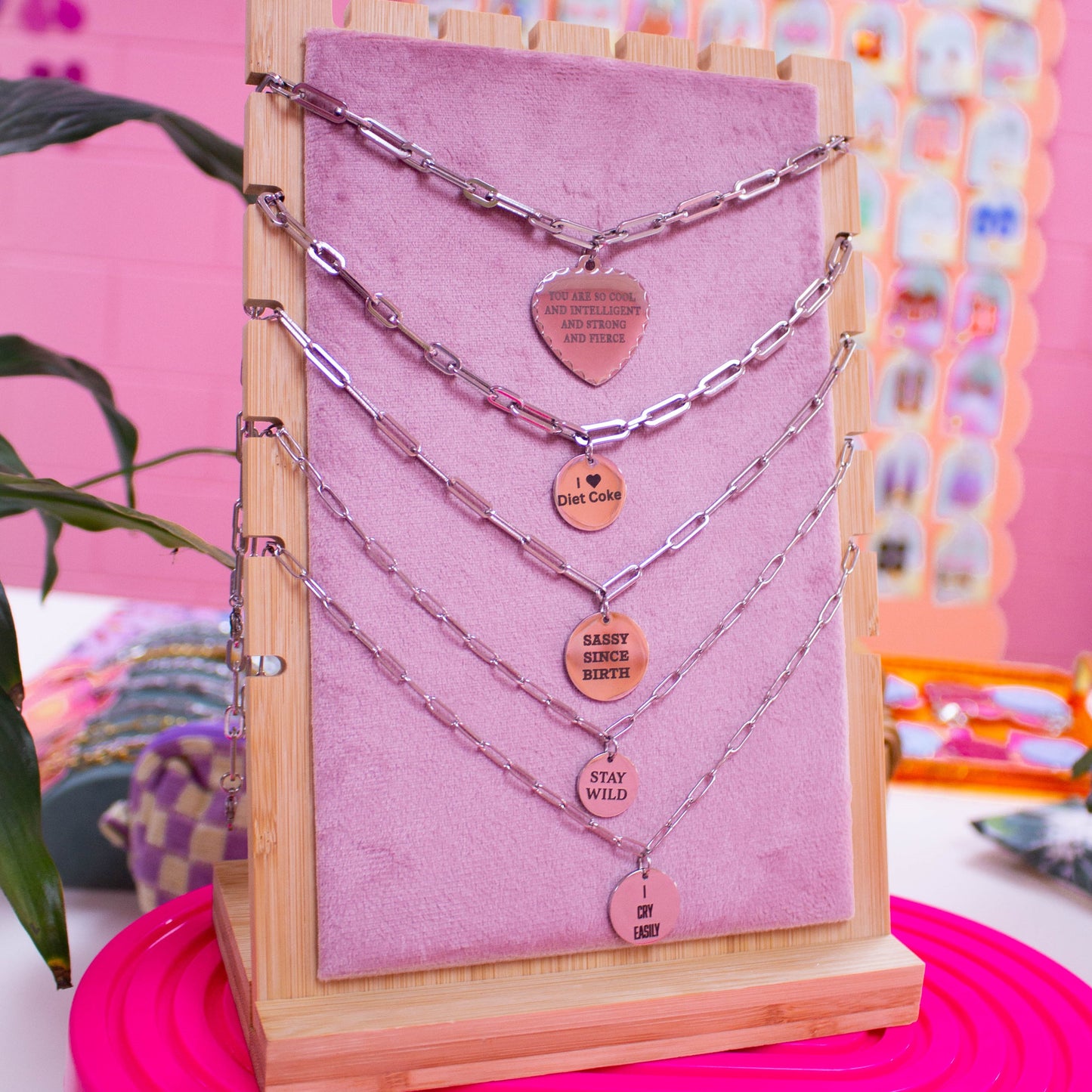 Engraved charm necklaces in silver show on display stand