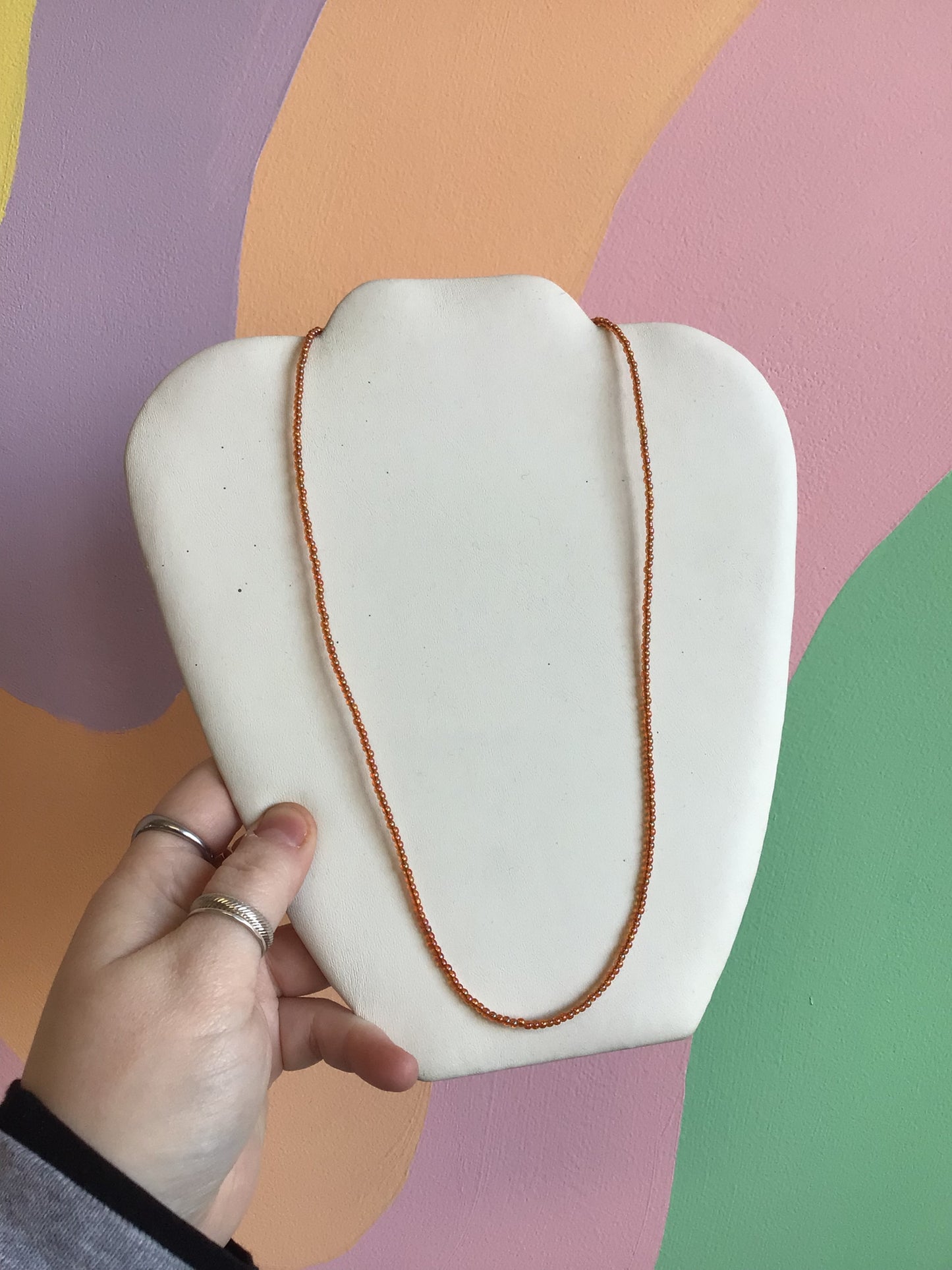 A necklace made up of organic shaped small seed beads, in a burnt-orange color.