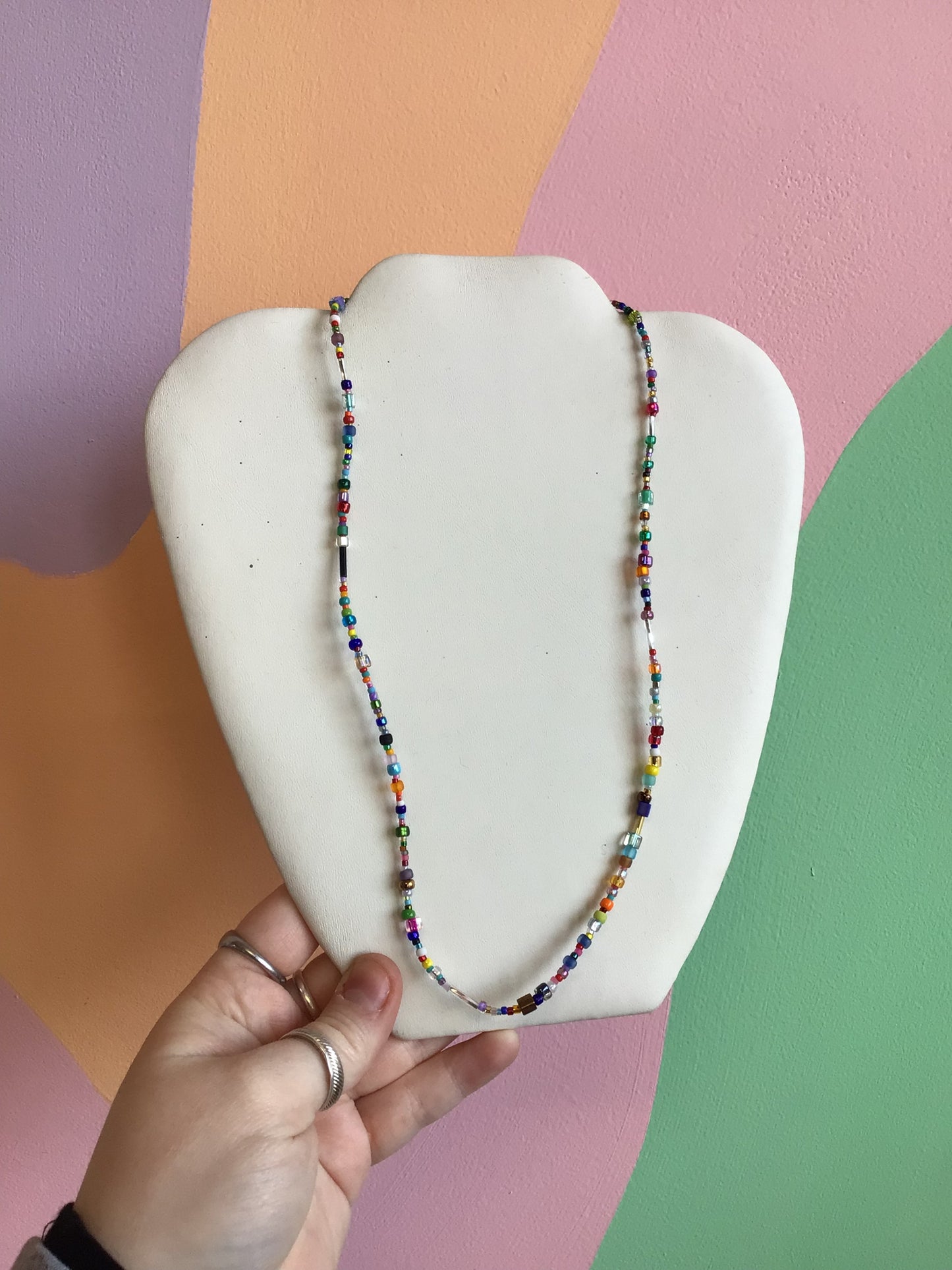 A necklace made up of a mixture of small beads in a variety of colors. Mainly cooler reds, blues, and neutrals.